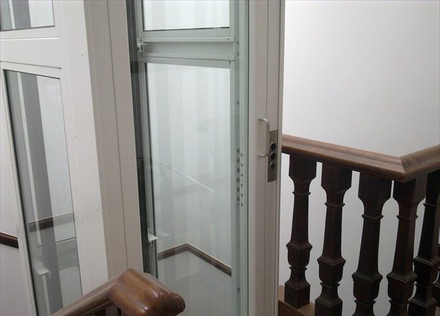 Elevador Primelift junto a escadaria com corrimão de madeira
